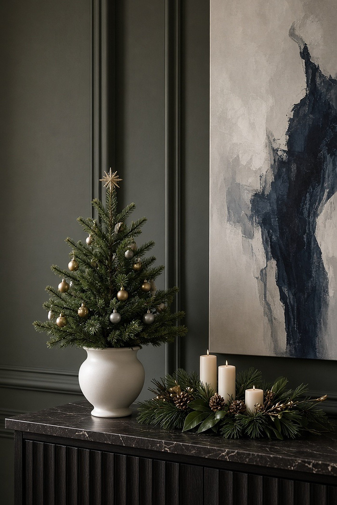 Small tabletop Christmas tree in a white ceramic urn on a console table with candles and greenery